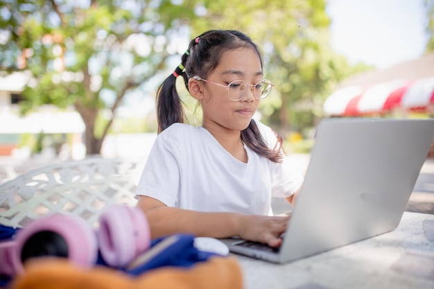 La bambina usa un computer portatile per imparare a scuola Il bambino sorride felice e ottiene la conoscenza a distanza