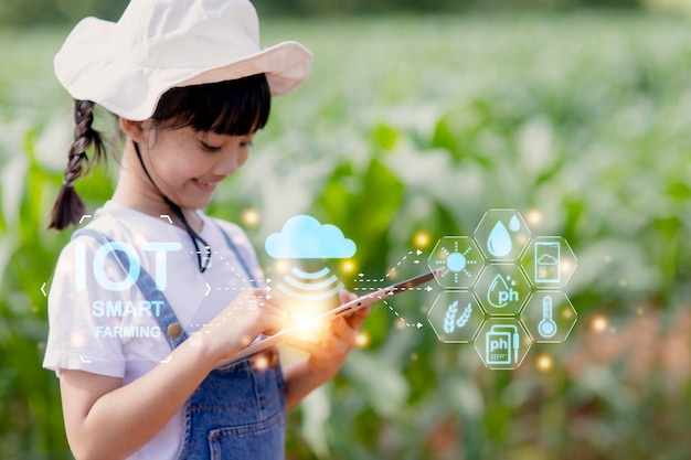 La bambina utilizza un tablet per analizzare la crescita delle piante nella trama agricola e l'icona visiva il concetto di tecnologia agricola concetto di apprendimento agricolo intelligente