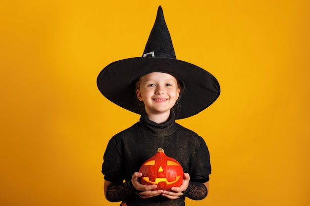 La bambina vestita in un costume da strega detiene la lanterna jack zucca