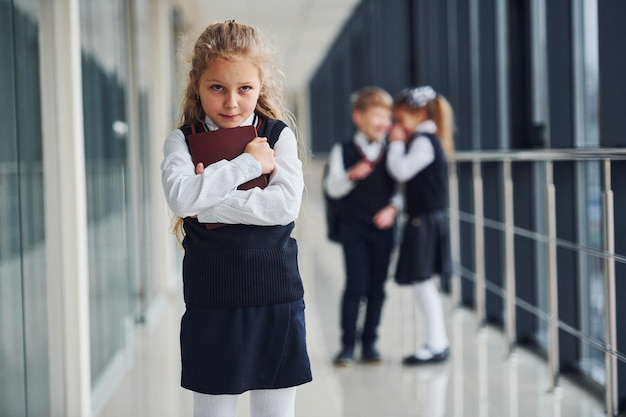 La bambina viene vittima di bullismo Concezione delle molestie I bambini delle scuole in uniforme insieme nel corridoio