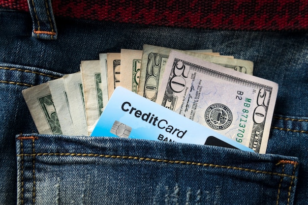 La banconota del dollaro americano e la carta di credito si chiudono nelle tasche dei jeans