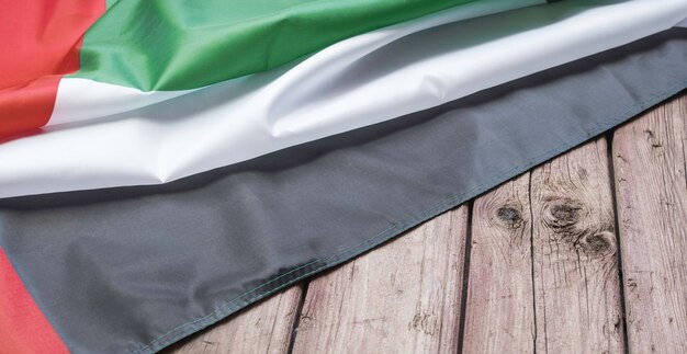 La bandiera degli Emirati Arabi Uniti giace su uno sfondo di legno marrone con spazio per testo o immagine