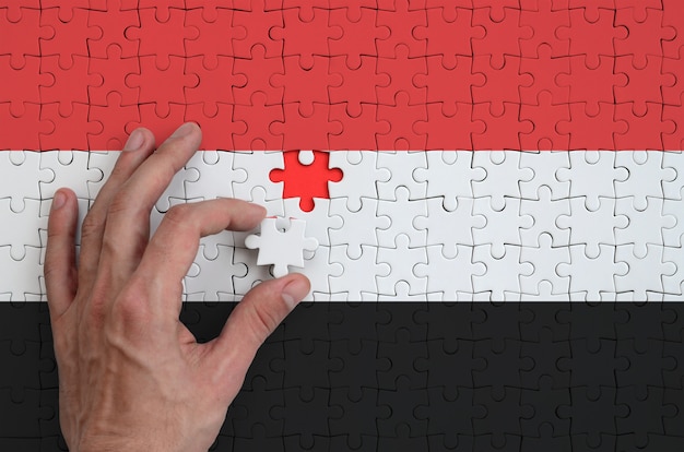 La bandiera dello Yemen è raffigurata su un puzzle che la mano dell'uomo completa per piegare