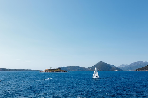 La barca a vela naviga lungo la costa del montenegro verso l'isola di Mamula