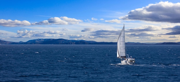 La barca a vela viaggia con l'aiuto del vento in mare calmo Bandiera di sfondo del cielo nuvoloso