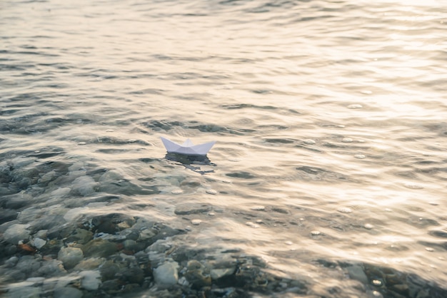 La barca di carta naviga sul mare sulla superficie dell'acqua blu.