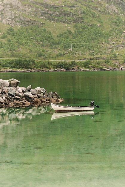 La barca e le rocce pittoresche si riflettono nell'acqua limpida, arcipelago delle Lofoten, contea di Nordland, Norvegia. Strada Turistica Nazionale Lofoten