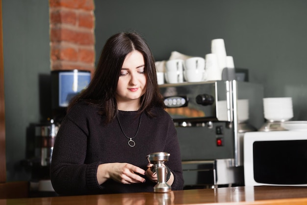 La barista della donna usa il pressino del caffè durante la preparazione dell'espresso