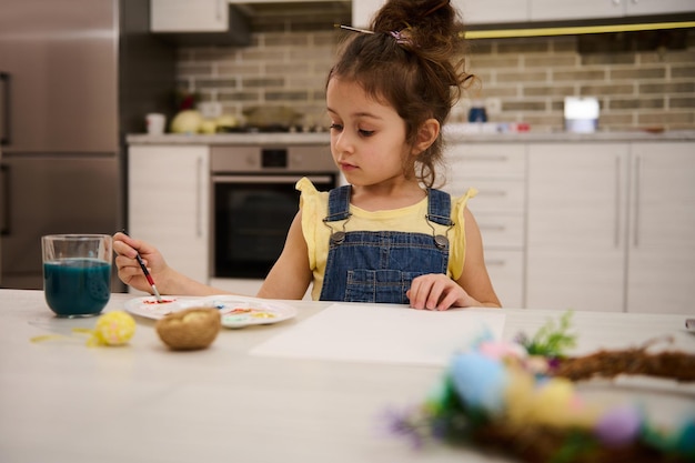 La bella bambina caucasica adorabile del bambino gode della pittura ad acquerello a casa