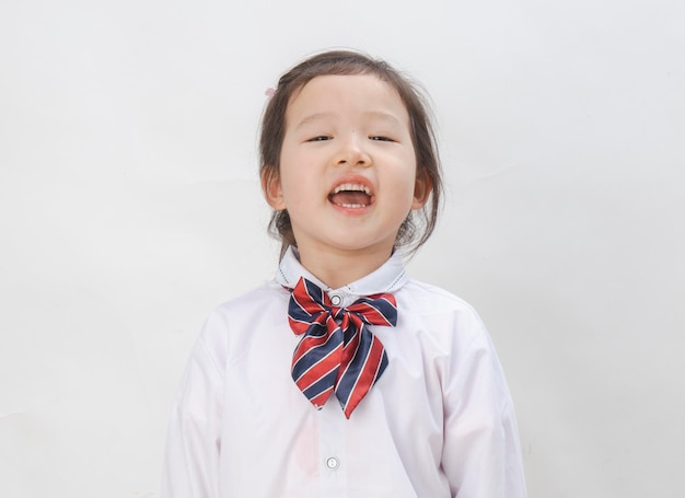 La bella bambina indossa un'uniforme scolastica su sfondo bianco