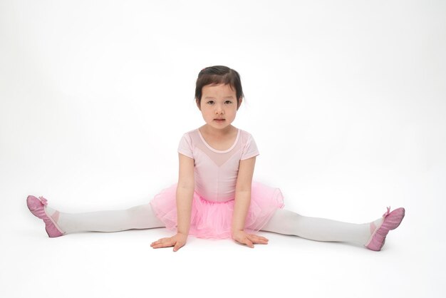 La bella bambina sta facendo ginnastica su uno sfondo bianco