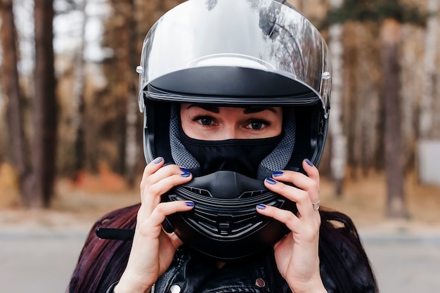 La bella bruna in un vestito su una moto nel parco