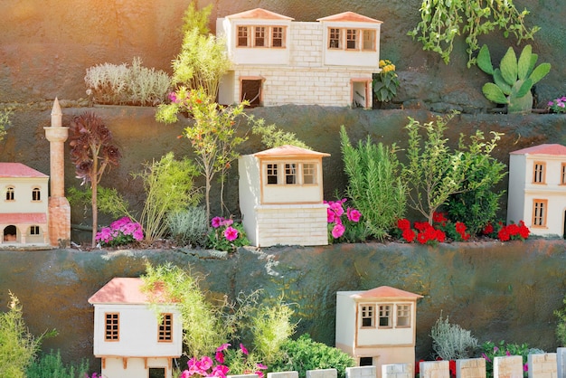 La bella composizione del giardino è composta da piante verdi, fiori rosa, case giocattolo in miniatura e la moschea sui gradini di pietra soleggiati