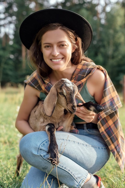La bella contadina con una piccola capra in campagna ha amicizia in natura