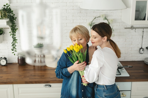 La bella donna adulta sta dando i fiori a sua madre matura. Festa della Donna