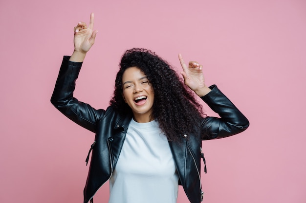 La bella donna afroamericana spensierata balla con le braccia alzate, si muove al ritmo della musica