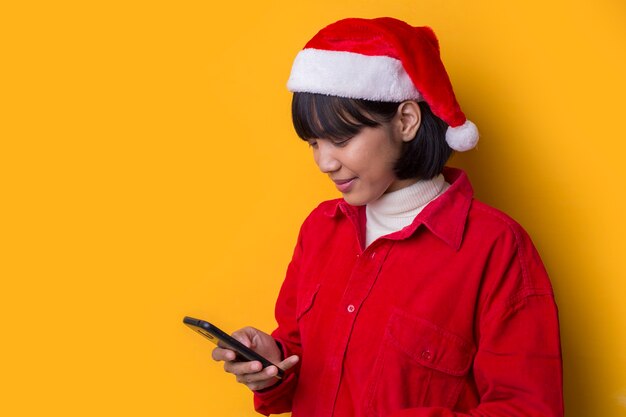 La bella donna asiatica del ritratto porta il cappello di natale della Santa