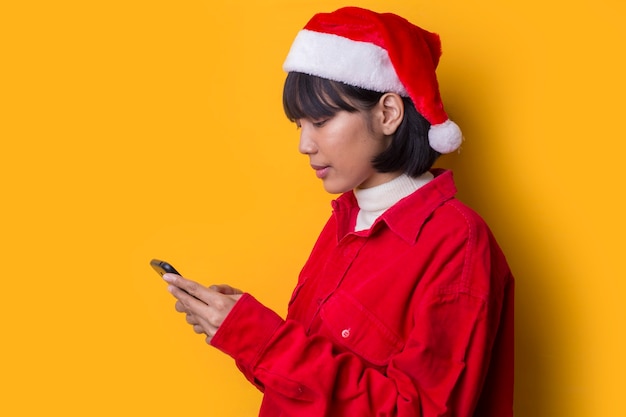 La bella donna asiatica del ritratto porta il cappello di natale della Santa