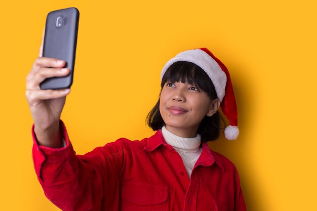 La bella donna asiatica del ritratto porta il cappello di natale della Santa