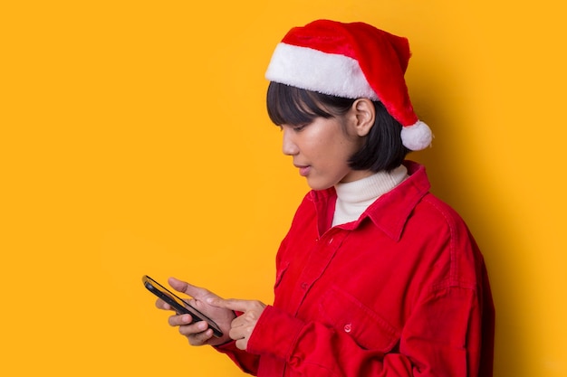 La bella donna asiatica del ritratto porta il cappello di natale della Santa