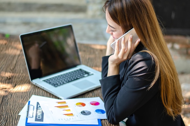 La bella donna asiatica di affari usa il taccuino del computer e lo Smart Phone nella caffetteria