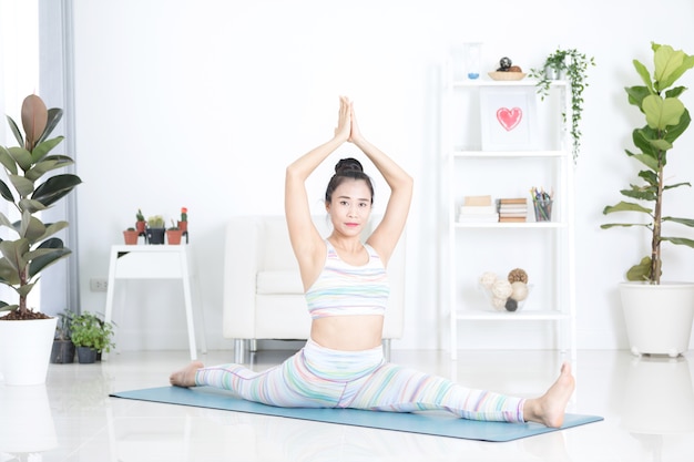 La bella donna asiatica di sport esegue gli esercizi a casa. Yoga