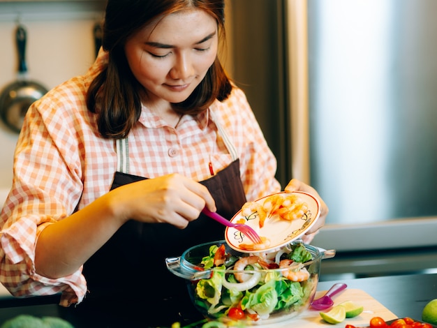 La bella donna asiatica durante fa l&#39;alimento degli spaghetti nella cucina