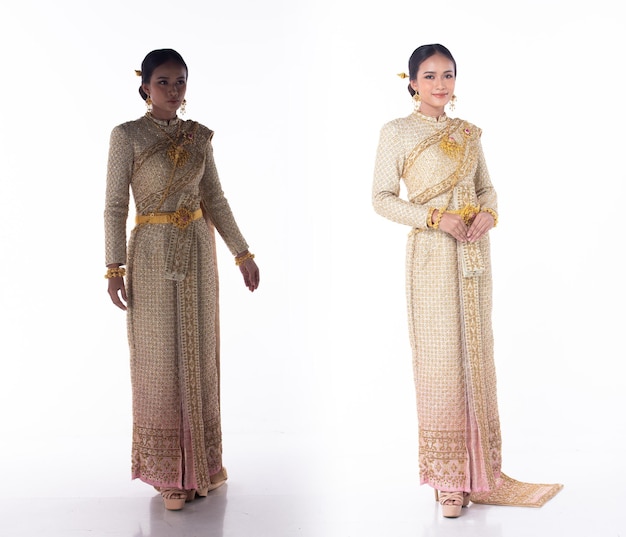 La bella donna asiatica indossa il costume tradizionale tailandese come abito da sposa nazionale della Tailandia con il corpo a figura intera isolato bianco degli articoli di moda decorativi dell'oro