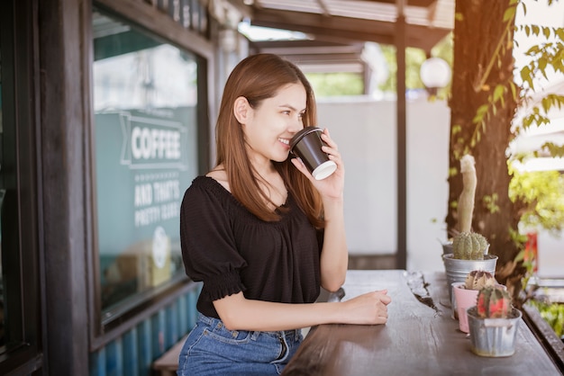 La bella donna asiatica sta bevendo il caffè