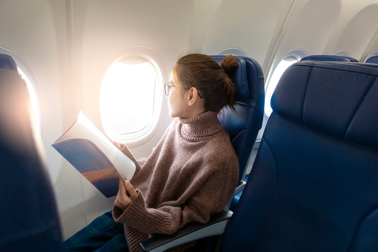 Foto la bella donna asiatica sta leggendo la rivista in aeroplano