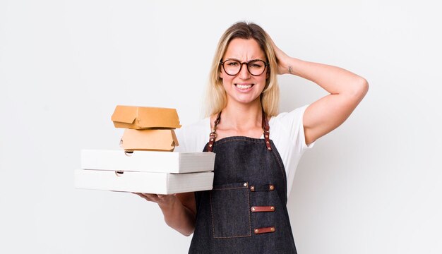 La bella donna bionda si sente stressata o spaventata con le mani sulla testa da portare via il concetto di fast food