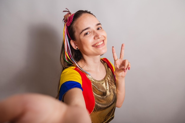 La bella donna brasiliana caucasica che indossa frevo copre la pace e l'amore di carnevale con le dita