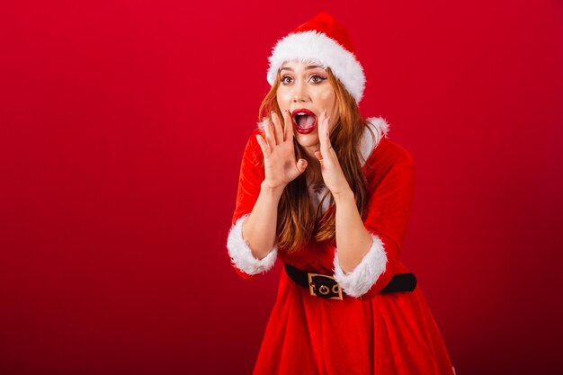 La bella donna brasiliana dai capelli rossi vestita di Natale veste la promozione gridante di Babbo Natale