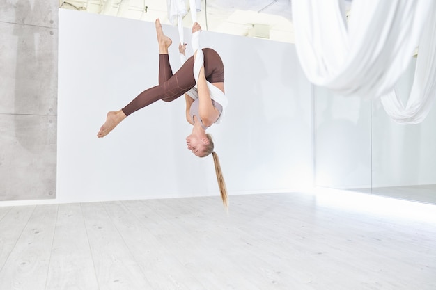 La bella donna caucasica esile sta facendo stretching in uno studio moderno e leggero