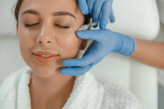 La bella donna caucasica sorridente sana sta facendo le procedure di bellezza alla stazione termale e al salone di sanità