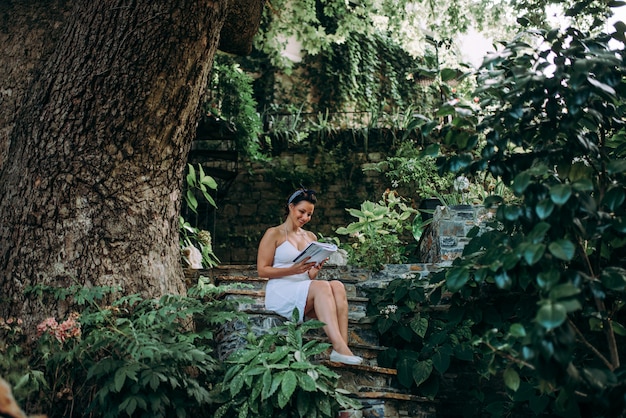 La bella donna che legge un libro in favola gradisce il giardino.