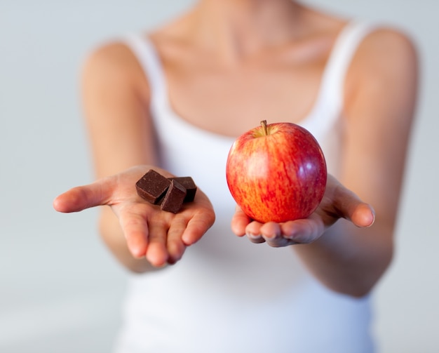 La bella donna che mostra il cioccolato e la mela mettono a fuoco su cioccolato