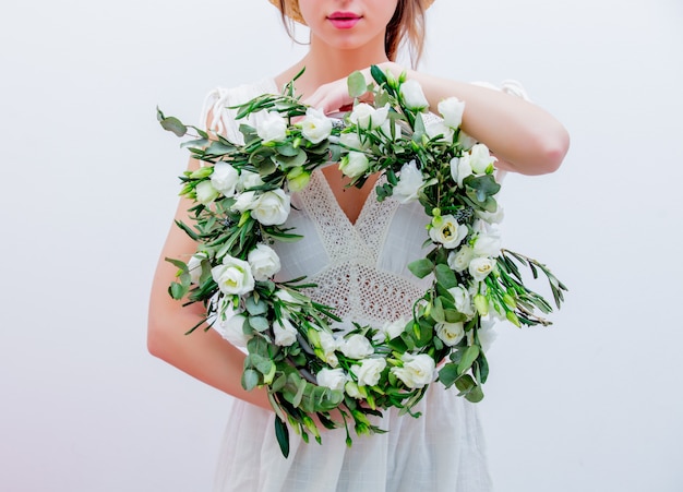 La bella donna con le rose bianche si avvolge su fondo bianco