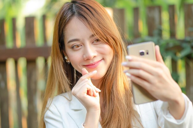 La bella donna d'affari asiatica usa selfiegirl dello smartphone per scattare foto per i social media attuali