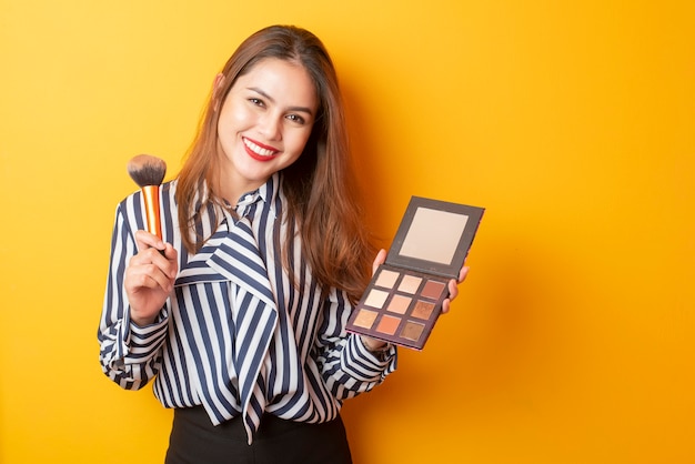 La bella donna del truccatore è felice su fondo giallo