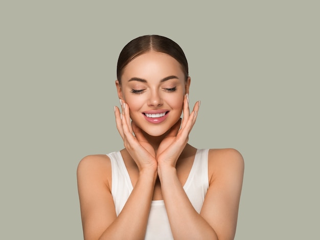 La bella donna del viso della pelle naturale compone la pelle sana che tocca il suo viso. Colore di sfondo. Verde