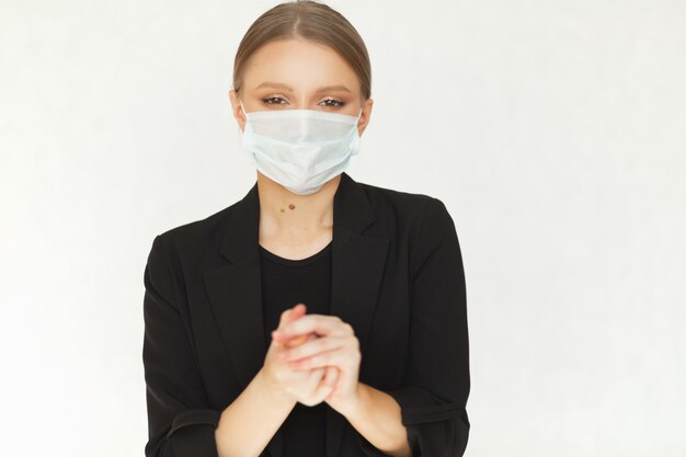 La bella donna di affari della donna in una maschera protettiva dai batteri pulisce le mani di un disinfettante