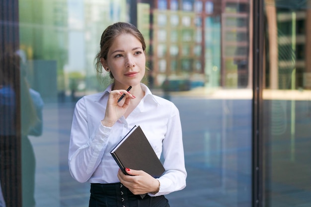 La bella donna di affari riuscita che sta contro le costruzioni del contesto scrive