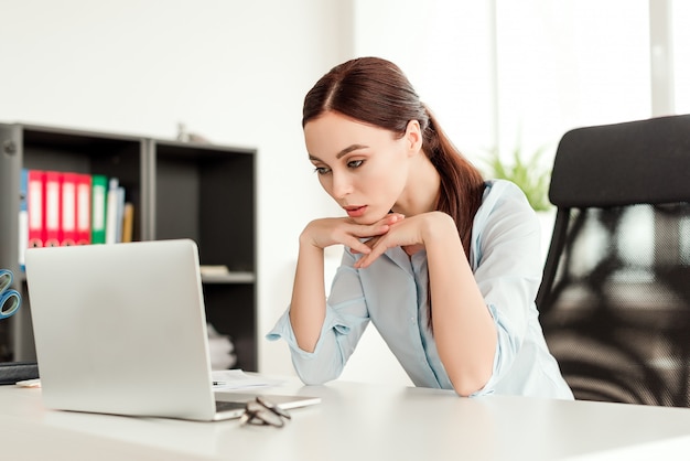 La bella donna di affari si è concentrata esaminando il computer portatile nel suo luogo di lavoro nell'ufficio