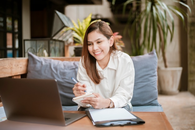 La bella donna di affari sta lavorando con il suo computer portatile in caffetteria