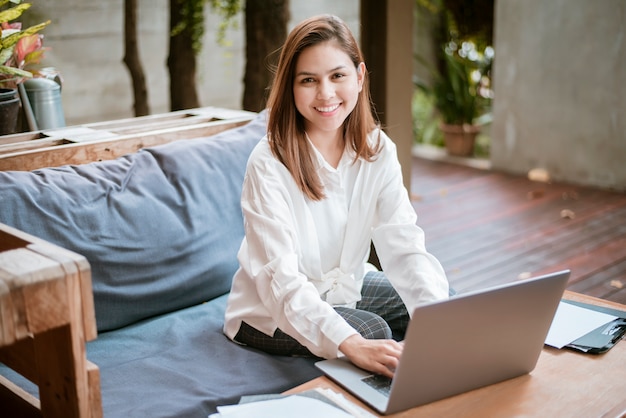 La bella donna di affari sta lavorando con il suo computer portatile in caffetteria