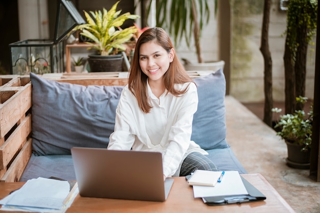 La bella donna di affari sta lavorando con il suo computer portatile in caffetteria