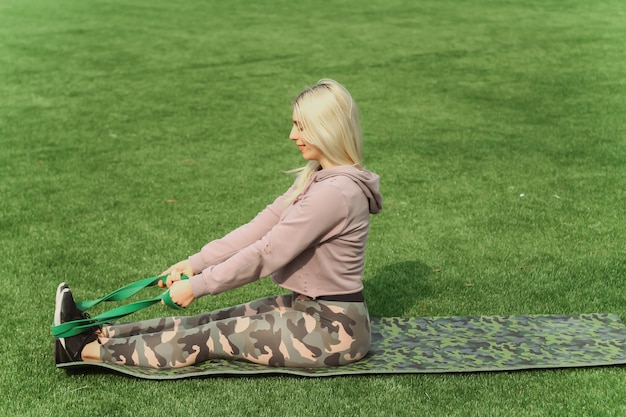 La bella donna di sport che fa l'allungamento della forma fisica si esercita nel parco della città all'erba verde