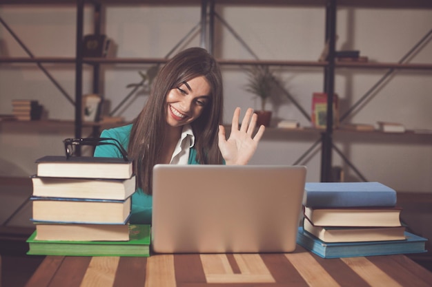 La bella donna è felice del suo lavoro di successo con il laptop grigio al tavolo