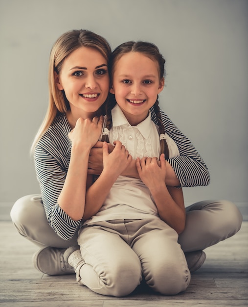 La bella donna e la sua piccola figlia sveglia stanno abbracciando.